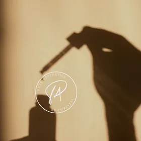 Shadow of a hand holding a dropper bottle beside the Pure Aesthetics logo