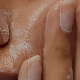 Close-up of fingertips resting on glowing skin beside the nose