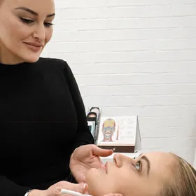 Chrystyl examining a client’s lower face on the treatment bed
